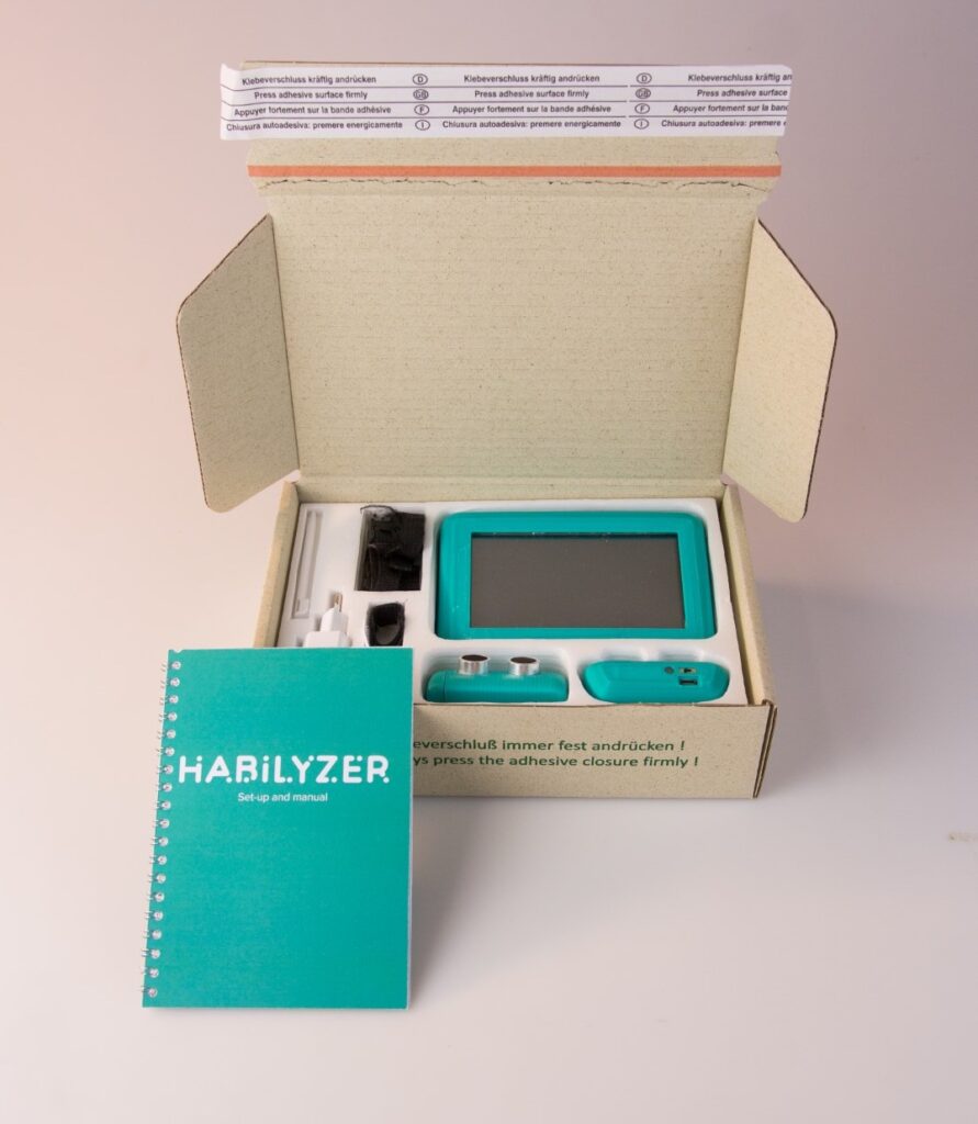 An image depicting the Habilyzer open-ended sensor kit. It shows the kit in a carton box, and a booklet with instructions sloped against it.