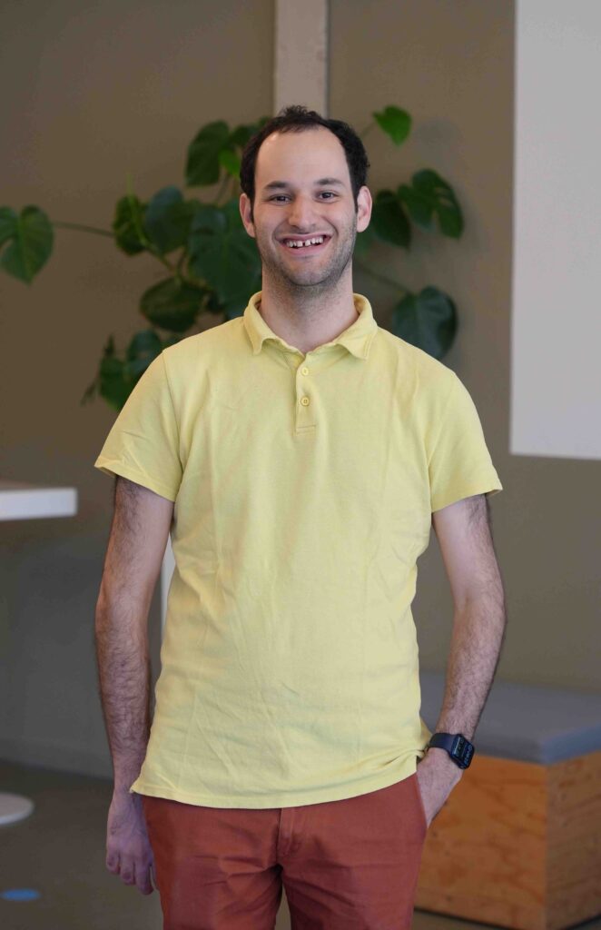 Image of this month's CHI NL Meet guest Peter Lovei. Peter is wearing a yellow polo shirt and red orange pants, and smiling.